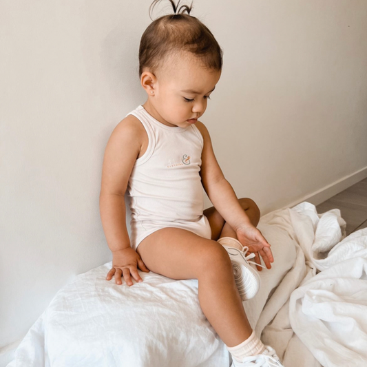 baby girl in beige bodysuit